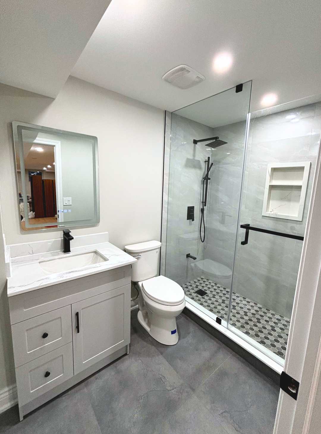 Grey vanity with white quartz counter, black shower faucet and