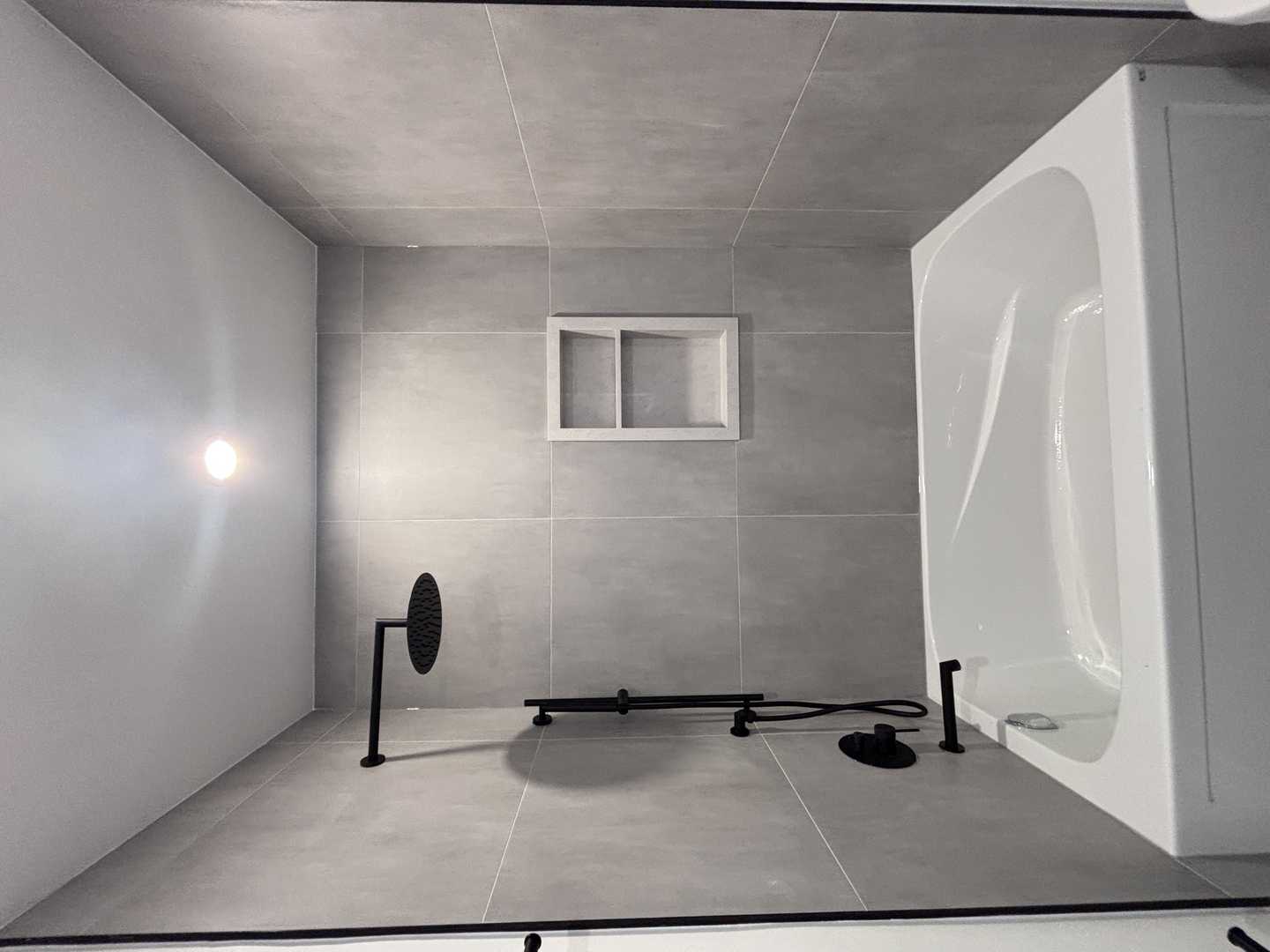 Black kodaen fixture with grey tone of tile and vanity,