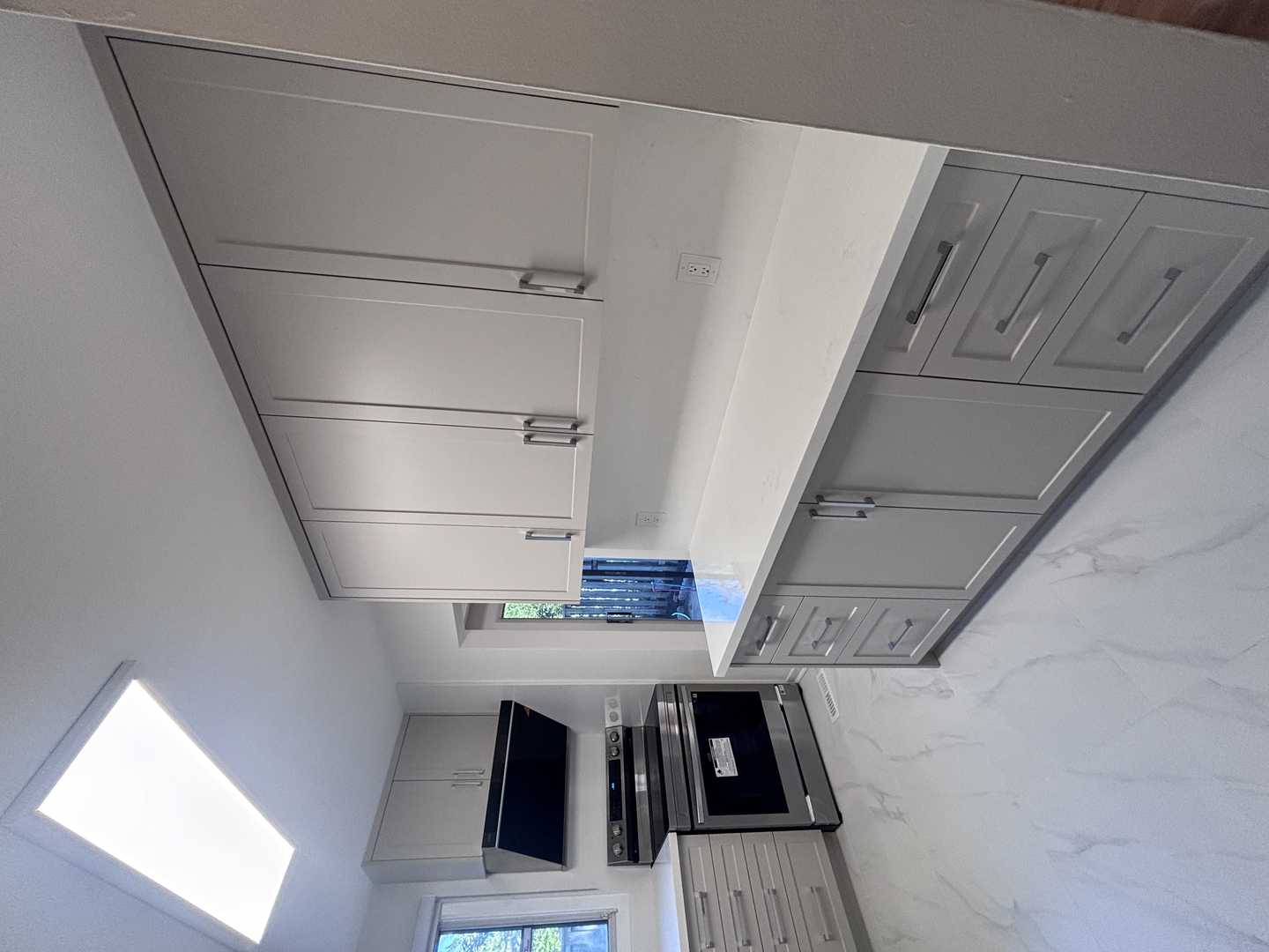 Light grey shaker kitchen cabinets w/ chrome fixtures. marble look