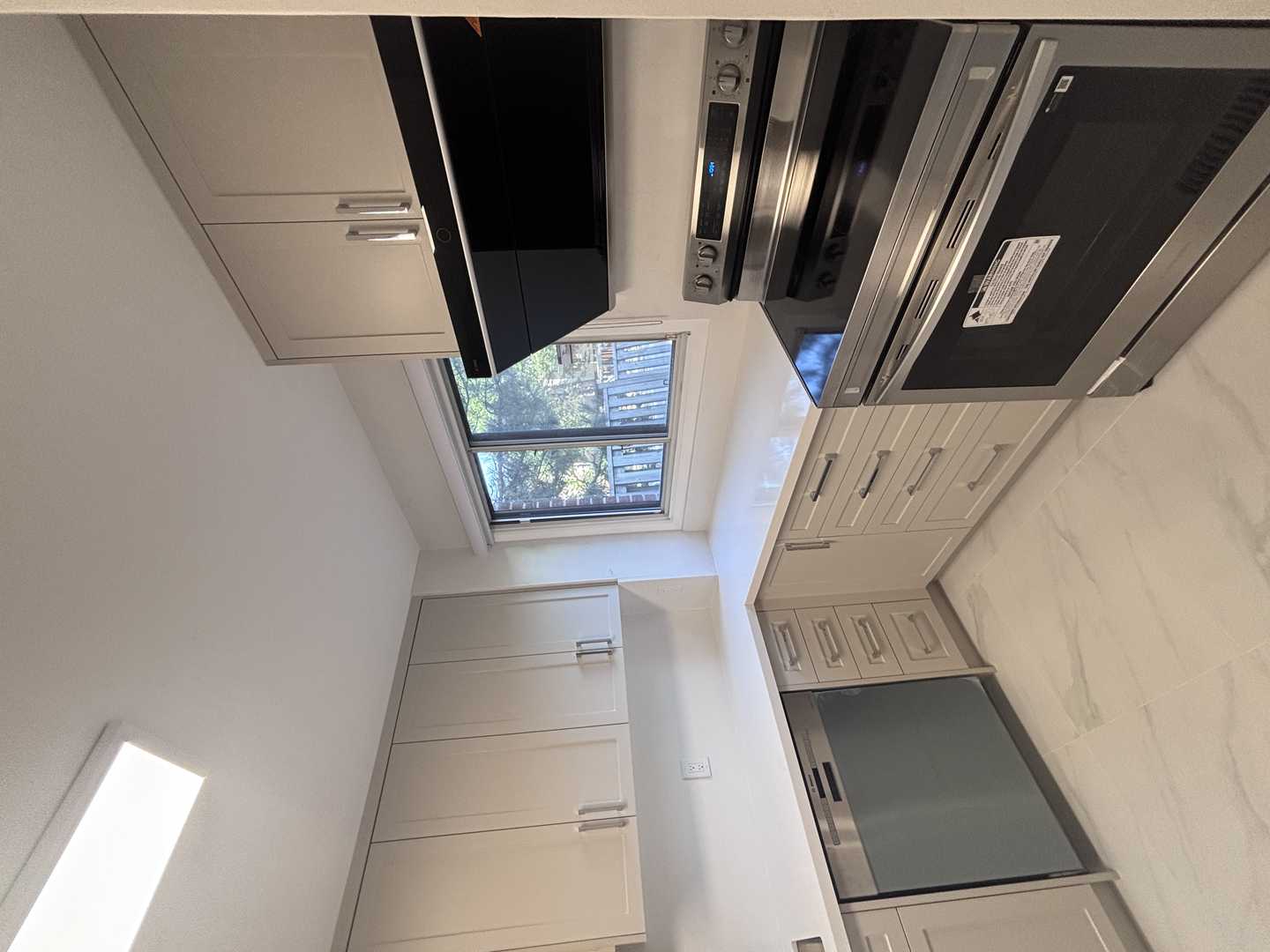 Light grey shaker kitchen cabinets w/ chrome fixtures. marble look