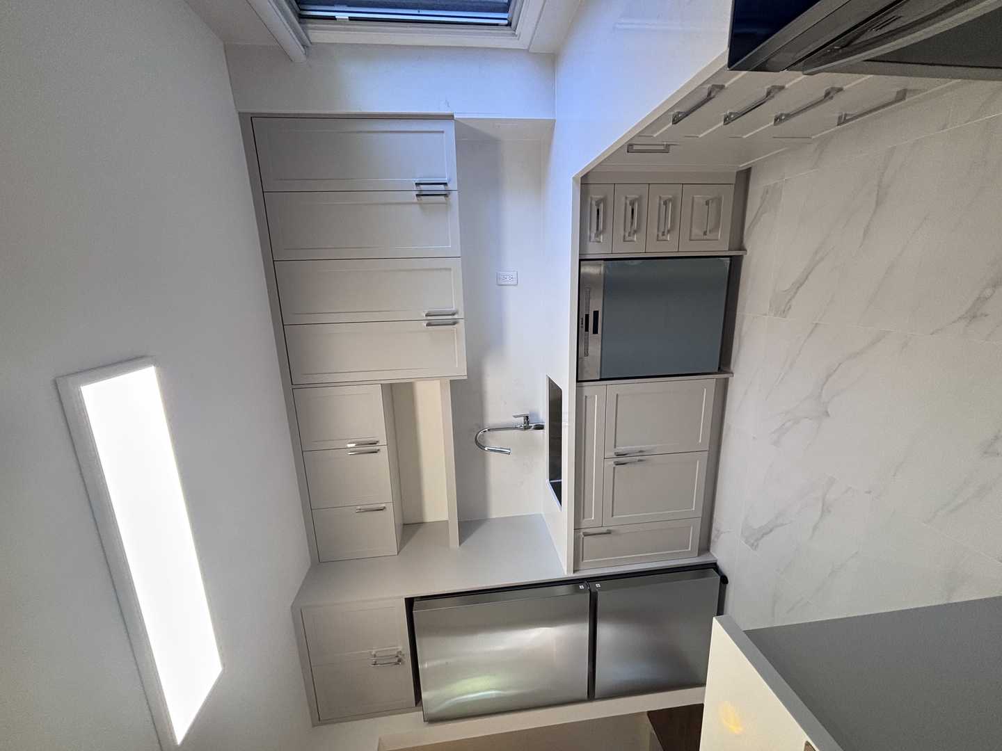 Light grey shaker kitchen cabinets w/ chrome fixtures. marble look