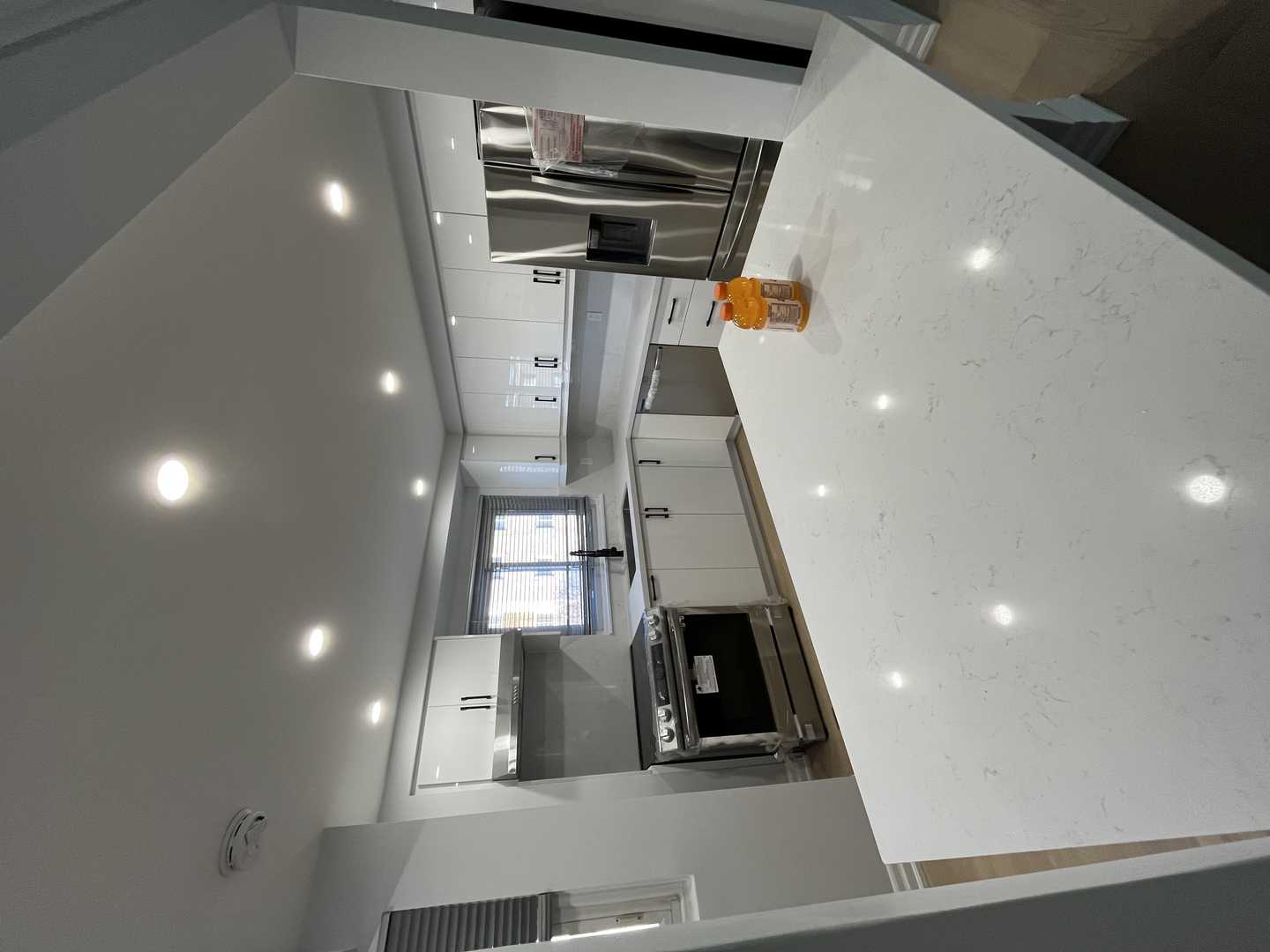 Black and white glossy finish walk-in pantry with black handles.