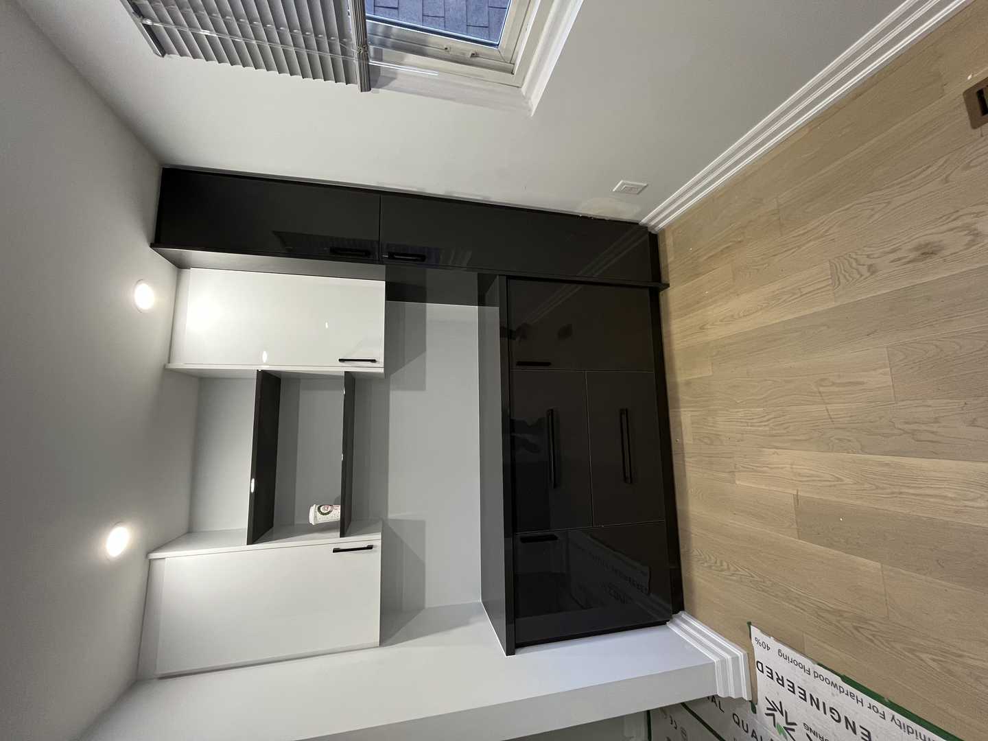 Black and white glossy finish walk-in pantry with black handles.