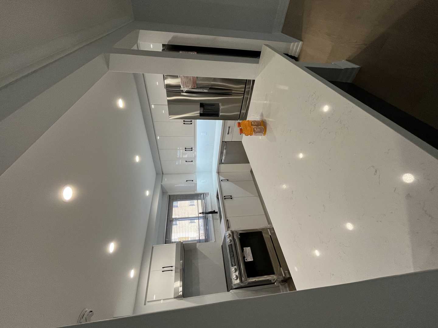 Black and white glossy finish walk-in pantry with black handles.