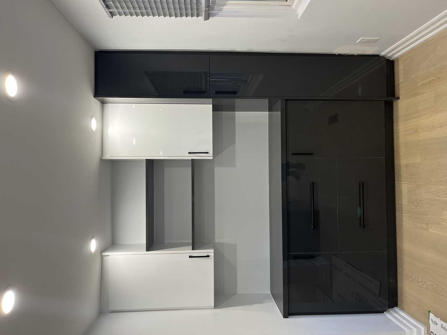 Black and white glossy finish walk-in pantry with black handles.